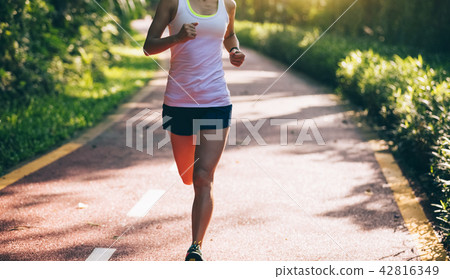 Fitnesswoman runner running on morning park road   42816349