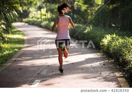 Fitnesswoman runner running on morning park road   42816350