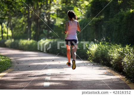 Fitnesswoman runner running on morning park road   42816352