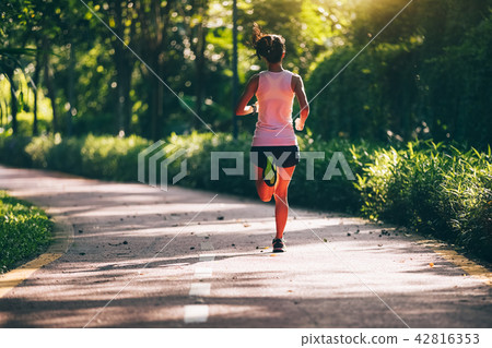 Fitnesswoman runner running on morning park road   42816353