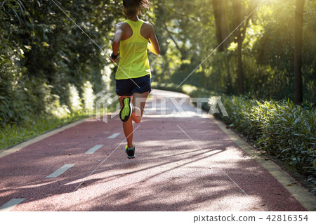 Fitnesswoman runner running on morning park road   42816354