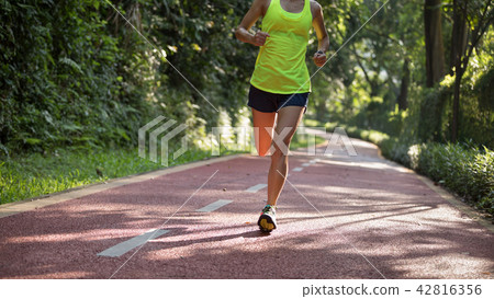 Fitnesswoman runner running on morning park road   42816356