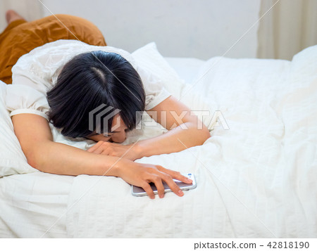 Woman with cellphone in bed - texting addiction Woman with cellphone in bed - texting addiction 42818190