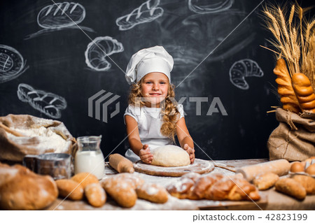 Little girl kneading dough at table Little girl kneading dough at table 42823199