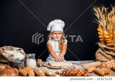 Little girl kneading dough at table 42823226