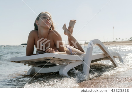 Young woman in chaise lounge at the sea beach Young woman in chaise lounge at the sea beach 42825818