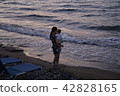 A woman holding a child in the evening sea 42828165