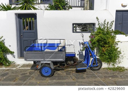 Motor tricycle parked against whitewashed house. 42829600
