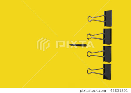 four big paper clips against little pencil 42831891