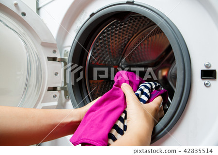 Photo of female hands folding colorful things in washing machine with open door Photo of female hands folding colorful things in washing machine with open door 42835514