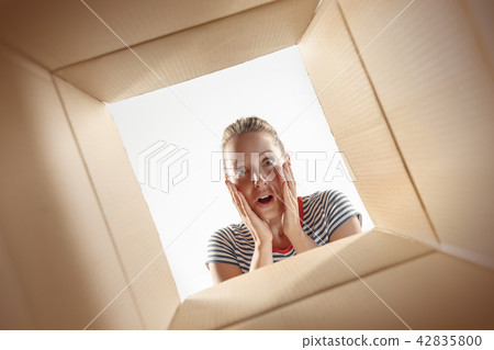 Woman unpacking and opening carton box and looking inside Woman unpacking and opening carton box and looking inside 42835800