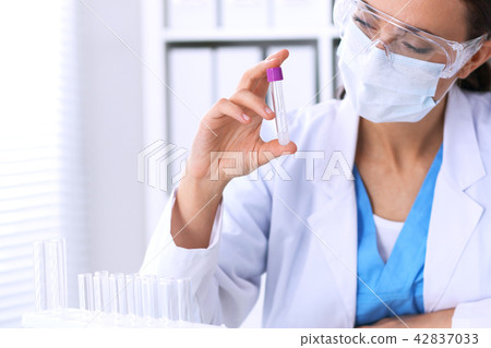 Female scientific research is looking at the tube in laboratory. Blood test concept Female scientific research is looking at the tube in laboratory. Blood test concept 42837033