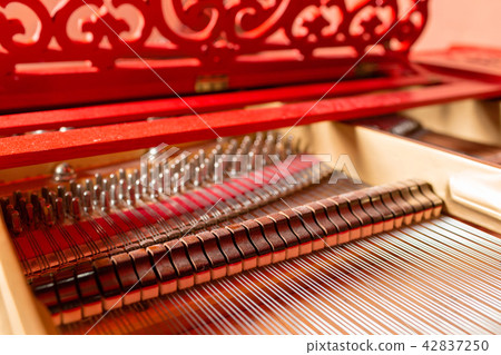 Strings inside a red grand piano. Piano playing, dampers, felt hammers, bronze strings and metal Strings inside a red grand piano. Piano playing, dampers, felt hammers, bronze strings and metal 42837250