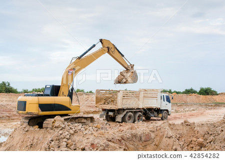 Yellow excavator machine loading soil into a dump Yellow excavator machine loading soil into a dump 42854282