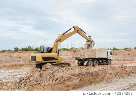 Yellow excavator machine loading soil into a dump Yellow excavator machine loading soil into a dump 42854292