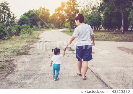 Mother holding a hand of his daughter walk Mother holding a hand of his daughter walk 42855220