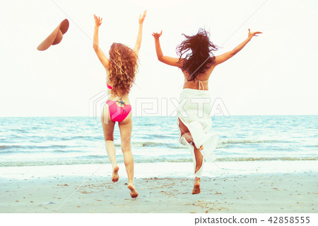 Happy women jumping on sand beach in summer. 42858555