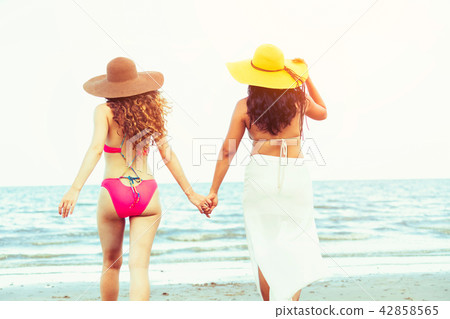 Happy women go sunbathing at sand beach in summer. Happy women go sunbathing at sand beach in summer. 42858565