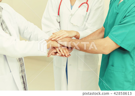 Doctor, surgeon and nurse join hands together. 42858613