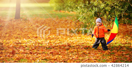 Child standing with umbrella in beautiful autumnal day 42864214