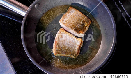 Pan-fried fish, Two pieces of loban fillet on the steaming frying pan. 42866713