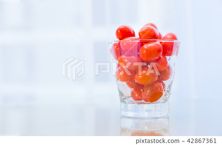 Juicy wet red tomatoes in clear glass cup Juicy wet red tomatoes in clear glass cup 42867361