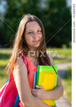 Girl schoolgirl in summer in park in nature. Hands holding a notebook of a folder behind a backpack Girl schoolgirl in summer in park in nature. Hands holding a notebook of a folder behind a backpack 42868492