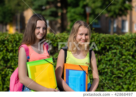Two girls schoolgirl teenager in summer in park after school. Hands holding a folder of notebooks Two girls schoolgirl teenager in summer in park after school. Hands holding a folder of notebooks 42868497