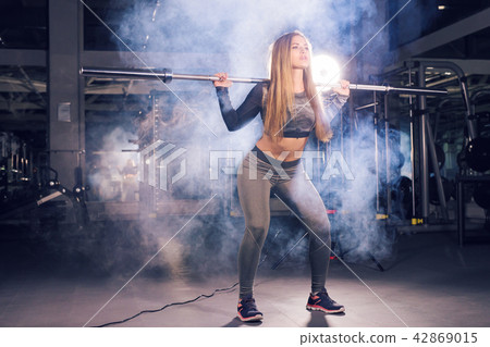 sport, fitness, training and happiness concept - sporty woman with barbell in gym 42869015