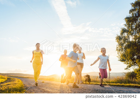 Playful family running and playing on a path in summer landscape 42869042