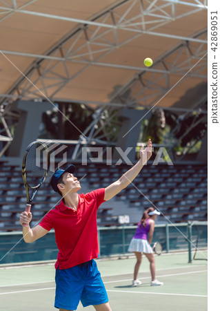 Asian tennis player ready to serve at the beginning of a doubles match 42869051