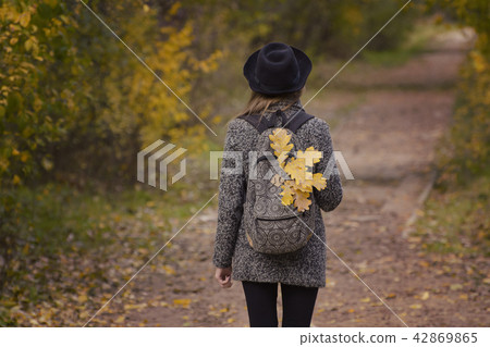 Yellow leaves in a backpack, a girl stands Yellow leaves in a backpack, a girl stands 42869865