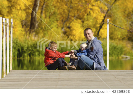 Father and two sons play on the pier. Autumn 42869868