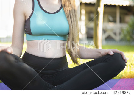 Pregnant woman in the garden on yoga mat Pregnant woman in the garden on yoga mat 42869872
