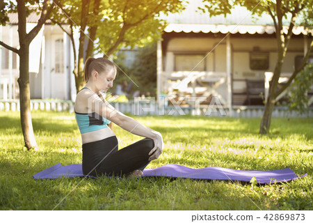 Pregnant woman in the garden practices yoga Pregnant woman in the garden practices yoga 42869873