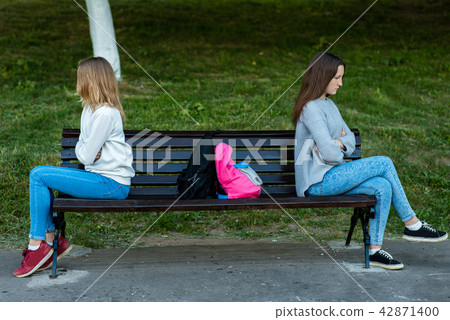 Two girls schoolgirl quarreled in the summer in park. They sit on a bench. The concept of conflict 42871400