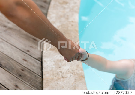 Man hand reach helpnig achild in a local pool on vacation. Man hand reach helpnig achild in a local pool on vacation. 42872339