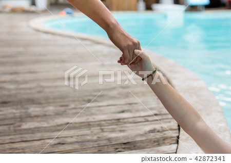 Man hand reach helpnig achild in a local pool on vacation. 42872341