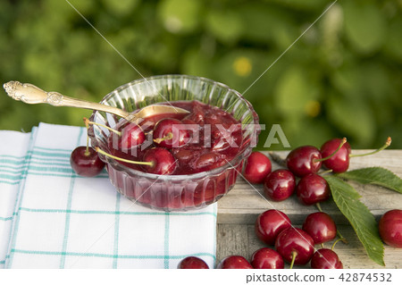 Fresh sweet cherries and marmalade bowl with teaspoon 42874532