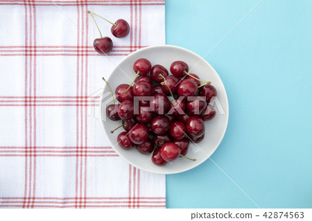 Fresh sweet cherries bowl, napkin on blue background 42874563