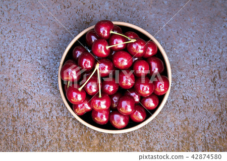 Fresh sweet cherries bowl on grunge rust background Fresh sweet cherries bowl on grunge rust background 42874580