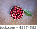 Fresh sweet cherries bowl with leaves on grunge rust background 42874582