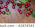 Fresh sweet cherries bowl with leaves on grunge rust background 42874583