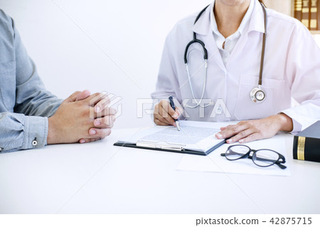 Doctor filling up an history form while consulting to patient an Doctor filling up an history form while consulting to patient an 42875715