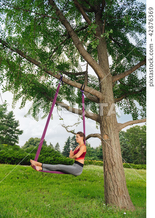 Dark-haired professional yoga teacher showing amazing fly yoga asana Dark-haired professional yoga teacher showing amazing fly yoga asana 42876369