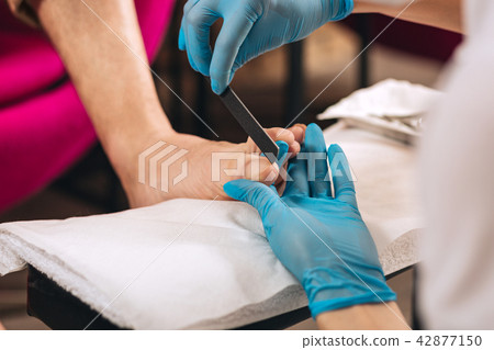 Female manicurist shaping nails on foot 42877150