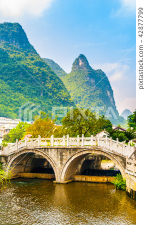 Small bridge over water and green peaks at Yangshuo, Guangxi Province, China Small bridge over water and green peaks at Yangshuo, Guangxi Province, China 42877799
