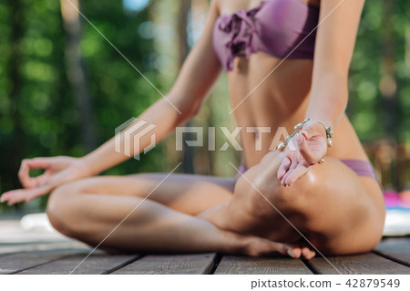 Slim woman sitting in lotus pose while meditating outdoors Slim woman sitting in lotus pose while meditating outdoors 42879549