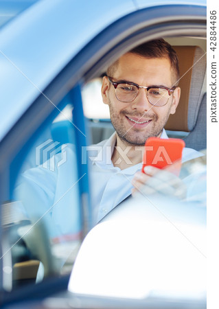 Delighted handsome man using his mobile device 42884486