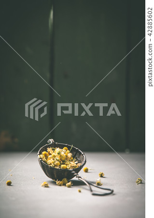 chamomile tea in strainer on vintage background chamomile tea in strainer on vintage background 42885602